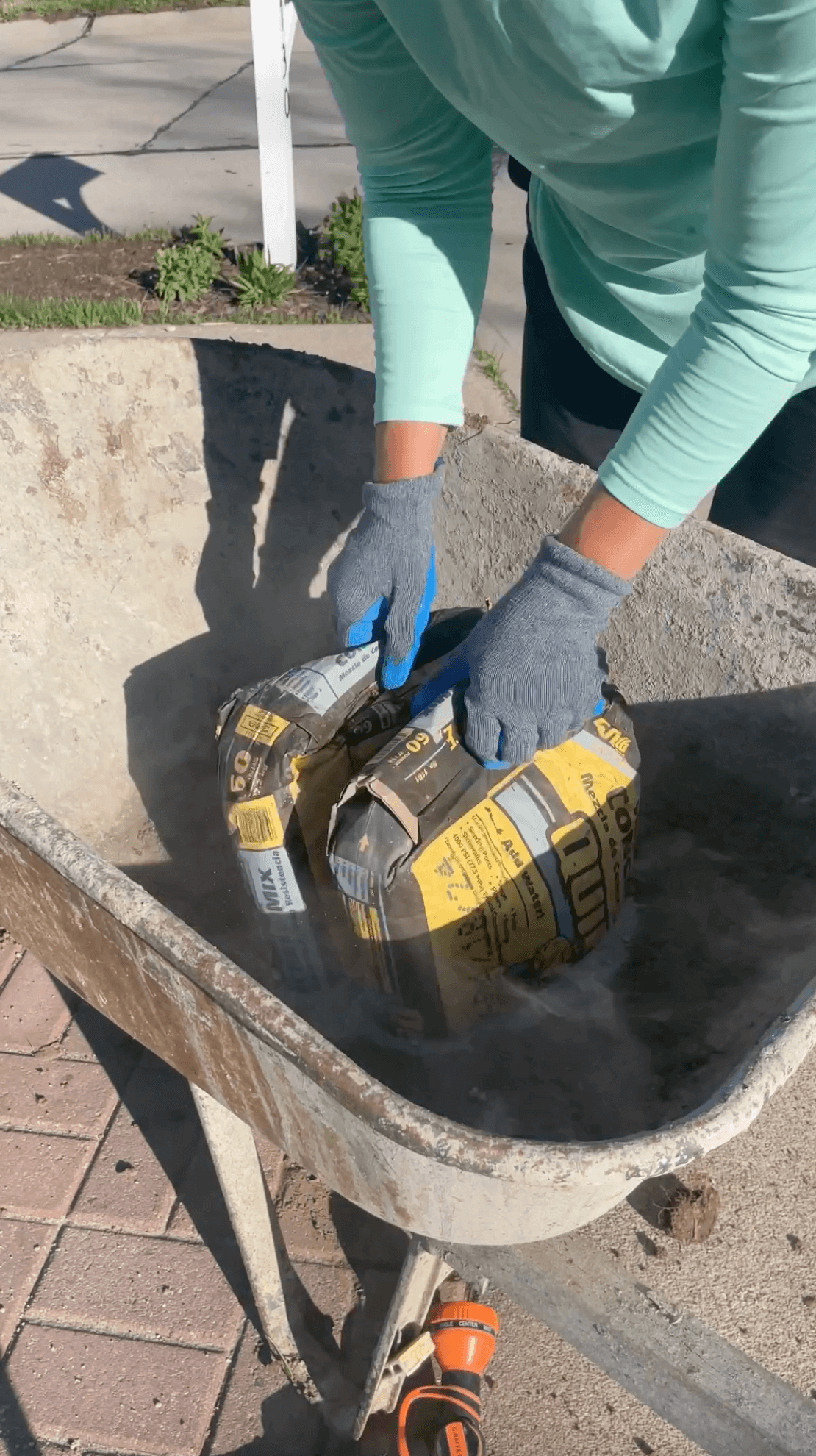 Pouring a bag of concrete into a wheel barrow. 